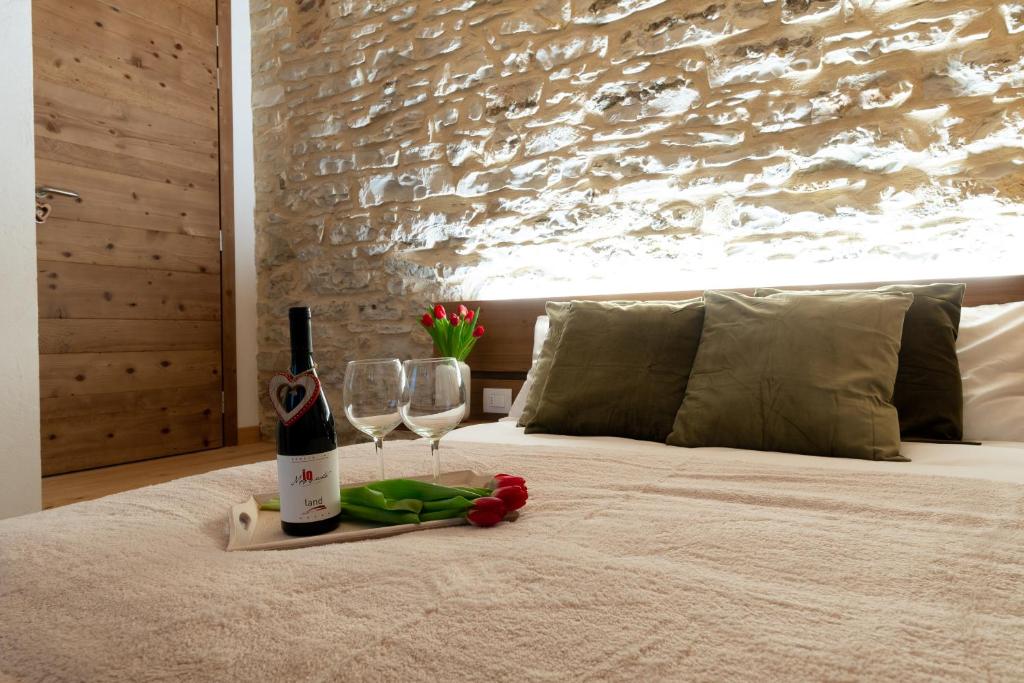 ConcoAntico Borgo Brunelli的床上有一瓶葡萄酒和两杯酒