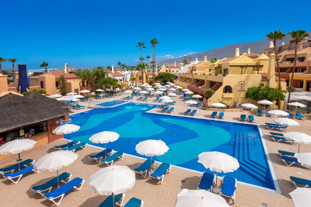 阿德耶阿德赫海岸塔哥洛家庭欢乐酒店的享有带椅子和遮阳伞的游泳池的上方景致
