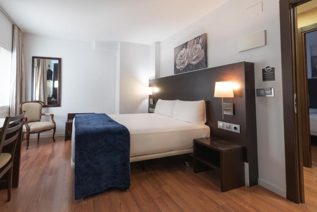 萨拉戈萨Hotel Alda Zaragoza Independencia的酒店客房带一张床、一张桌子和椅子