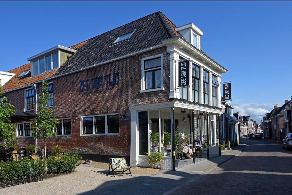 霍尔沃德Zee van Tijd Holwerd的街上的砖砌建筑,外面有人坐