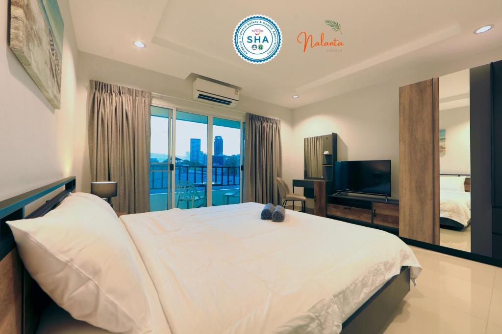 芭堤雅市中心Nalanta Hotel Pattaya的卧室配有一张白色大床和电视。
