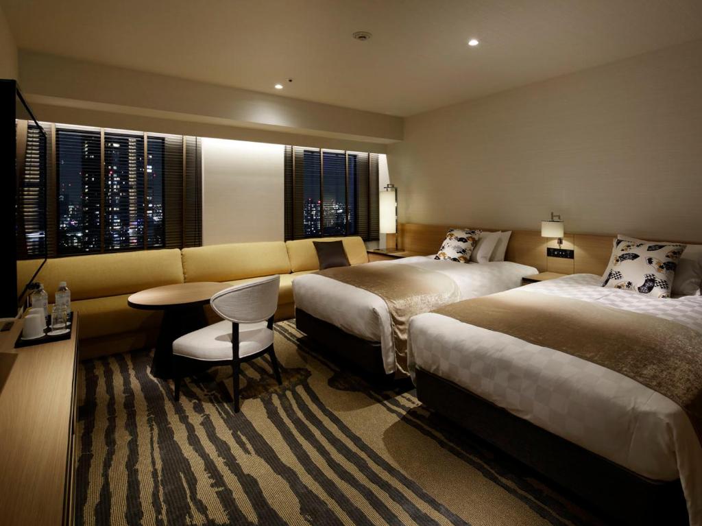 东京池袋阳光城王子酒店的酒店客房,设有两张床和一张沙发