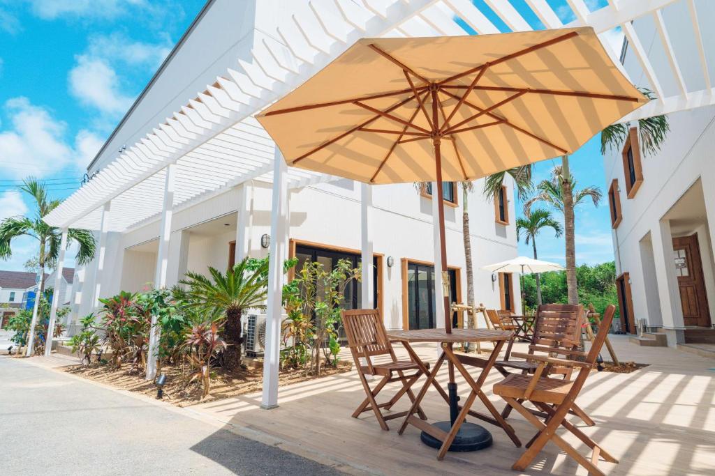 宫古岛Hotel California Miyakojima Resort的庭院里配有桌椅和遮阳伞