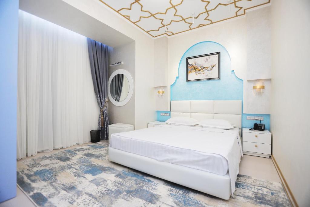 塔什干Reikartz Amirun Tashkent的卧室配有白色的床和蓝色的墙壁