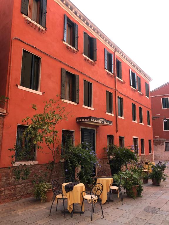 威尼斯阿尔伯格玛林酒店的前面有桌椅的红色建筑