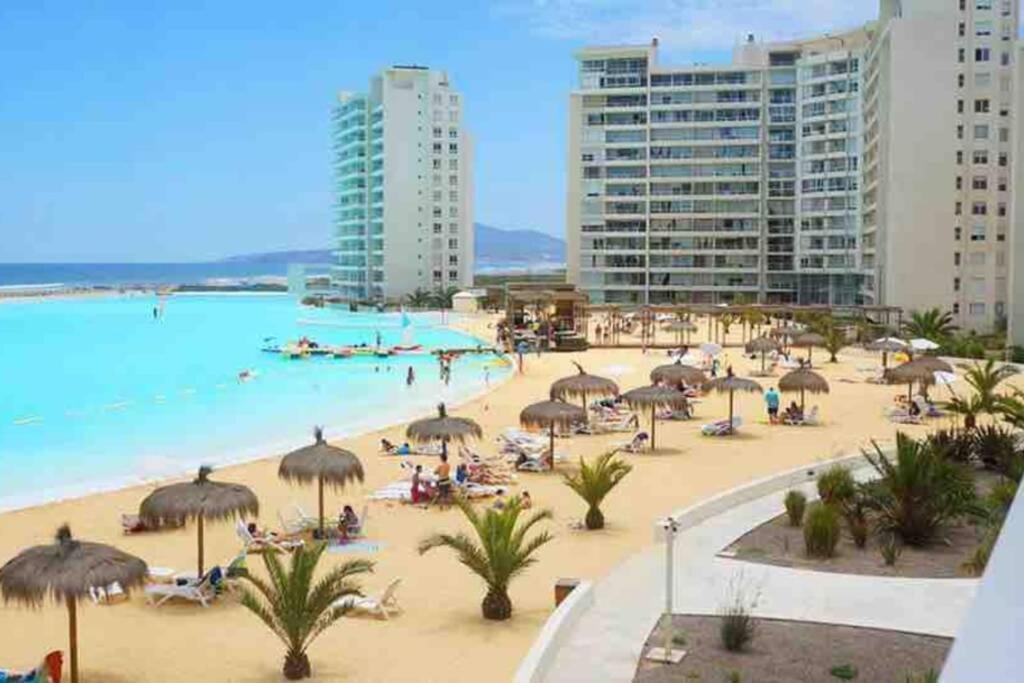 拉塞雷纳Hermoso apartamento de 2 dormitorios y 2 baños en Laguna del Mar La Serena的海滩上有遮阳伞和水中的人