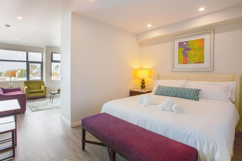 圣地亚哥One Bedroom Apartment with San Diego Downtown View的卧室配有一张白色大床和紫色长凳
