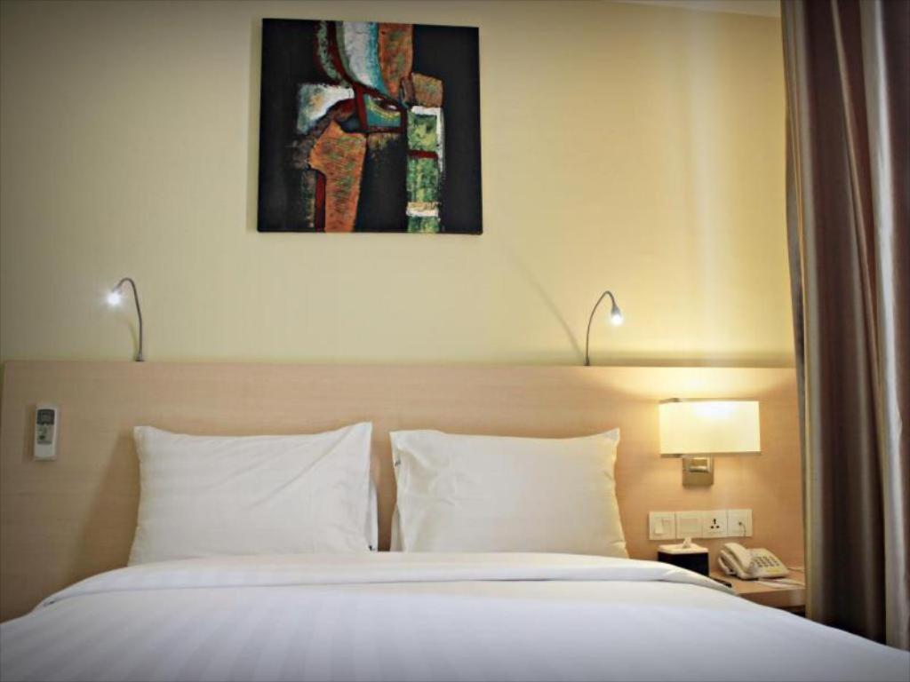 名古屋巴淡岛商务酒店的一张位于酒店客房的床铺,上面有一张照片