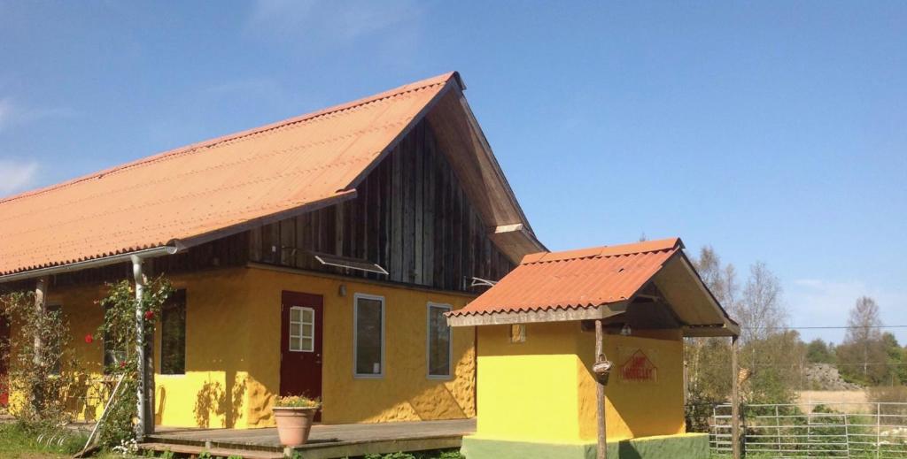 HishultLanthotellet Hishult的一座黄色的小房子,有橙色的屋顶