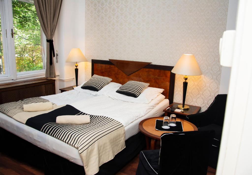 布达佩斯布达佩斯长荣旅馆的一间卧室配有两张床和一张桌子及椅子