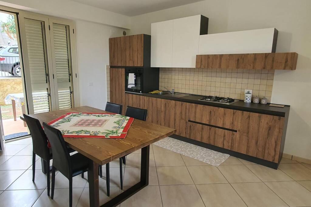 焦约萨马雷阿Appartamento Vacanza Mare Gioiosa Marea Zappardino的厨房配有木桌、椅子和炉灶