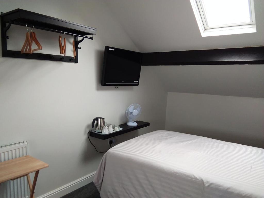 莱斯特Comfort Guest House的卧室配有一张床,墙上配有电视。