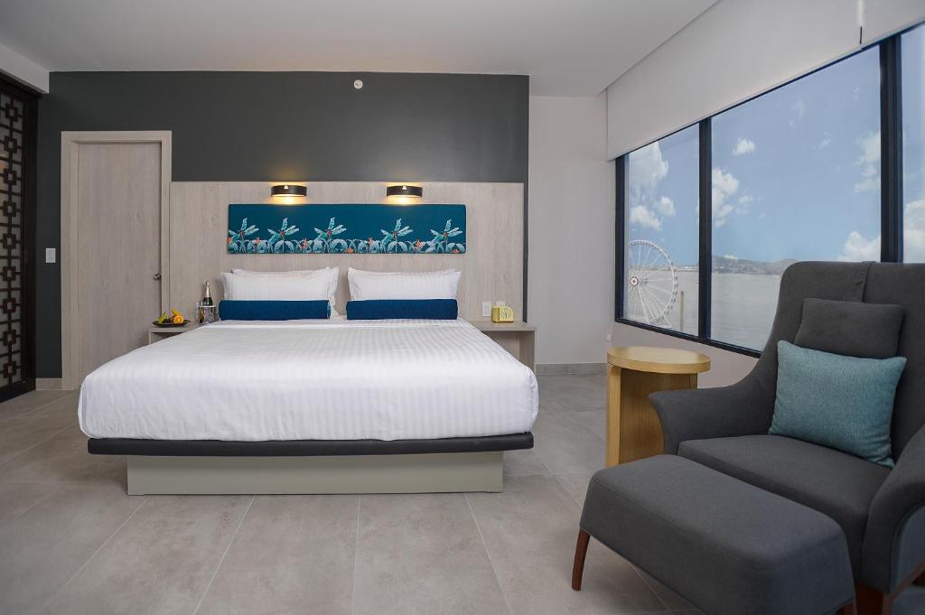 瓜亚基尔River Garden Hotel + Suites的一间卧室配有一张大床和一把椅子