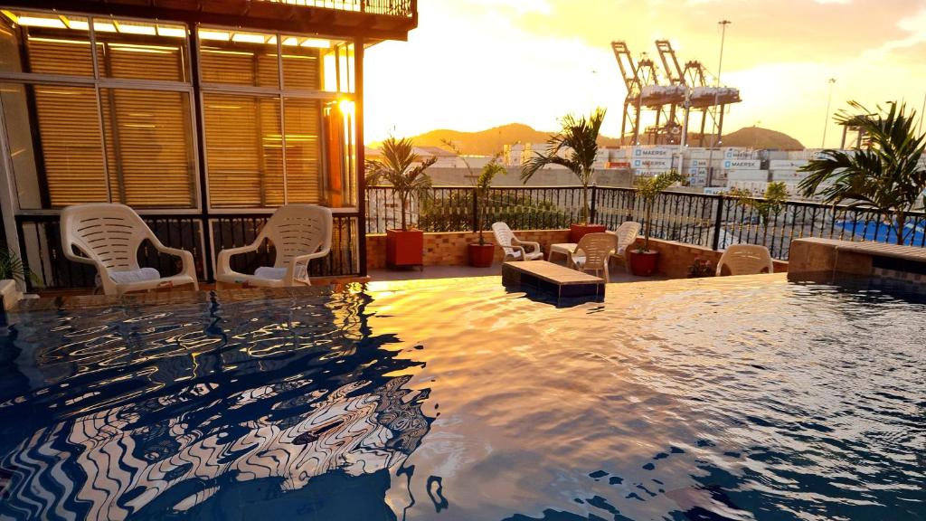 圣玛尔塔Hotel Carolina Del Mar的一座带白色椅子的游泳池和一座建筑
