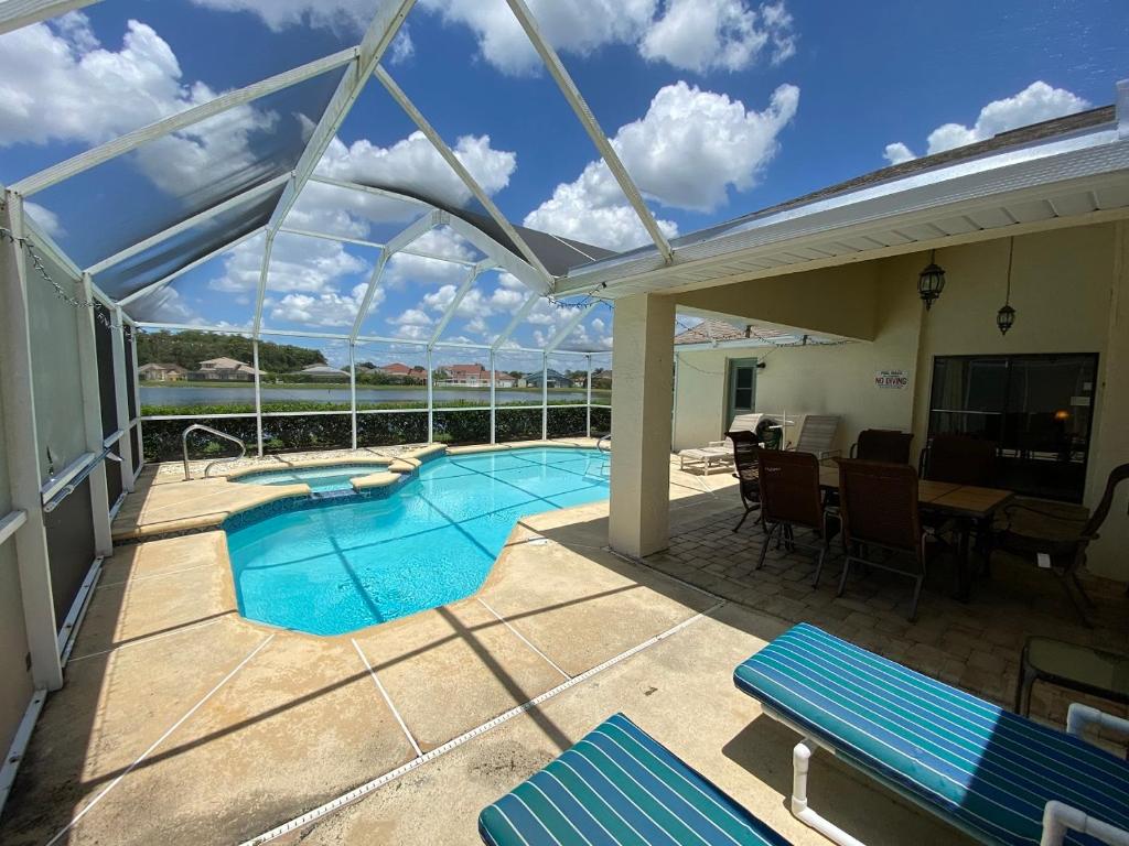 基西米All Homes With Private Pool的庭院设有游泳池、桌子和椅子。