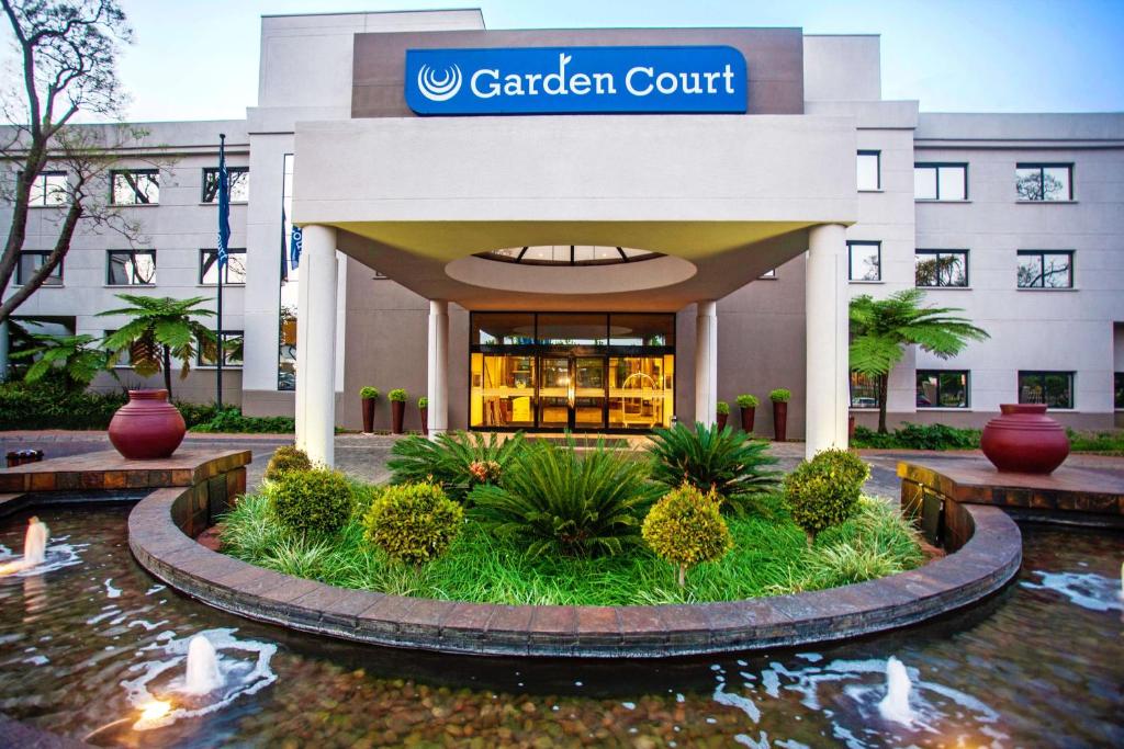 比勒陀利亚Garden Court Hatfield的花园庭院建筑,前面有一个池塘