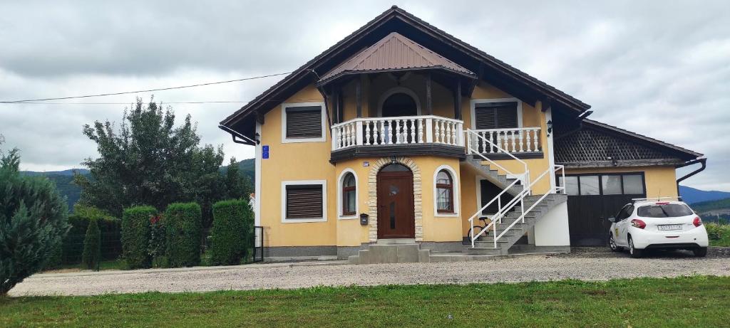 奥托查茨Apartman Majetić的前面有一辆白色汽车的黄色房子