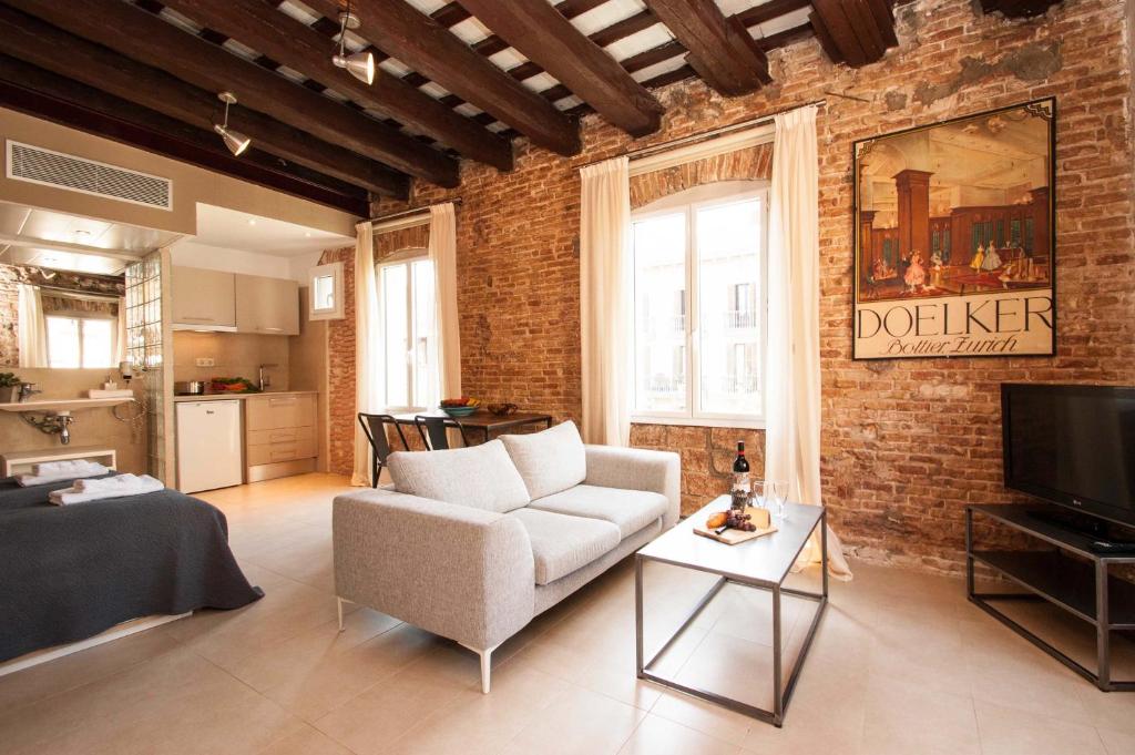 巴塞罗那Decô Apartments Barcelona-Born St.的客厅配有白色沙发和砖墙