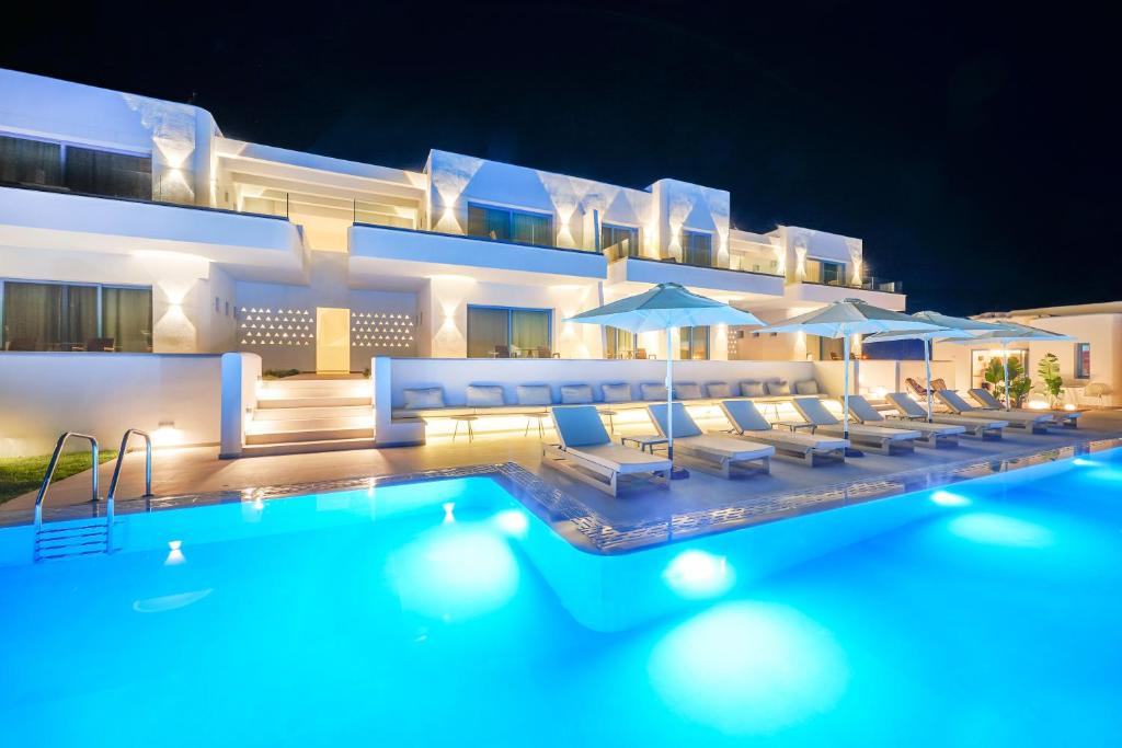 普利瑙港湾Narciso Thassos Luxury Suites的酒店设有带椅子和遮阳伞的游泳池