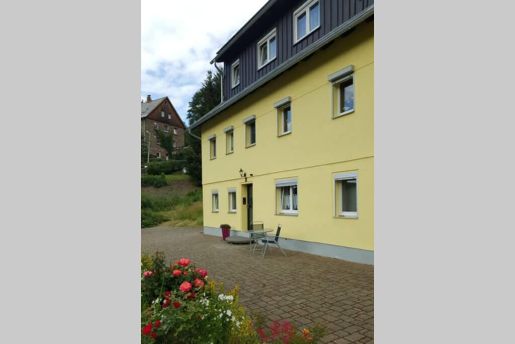 布赖滕布伦Sonnenblick Rittersgrün II的庭院里黄色的建筑,设有长凳