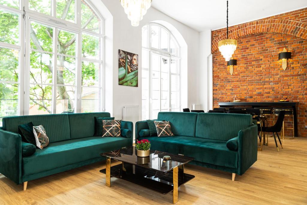 弗罗茨瓦夫Prestige Apartments 12的客厅配有2张绿色沙发和1台钢琴
