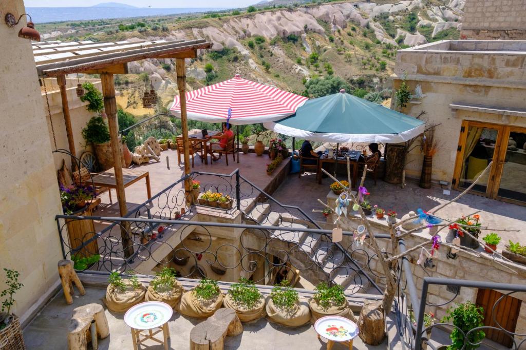 乌奇希萨尔Pigeon Hotel Cappadocia的享有带桌子和遮阳伞的天井的顶部景致。
