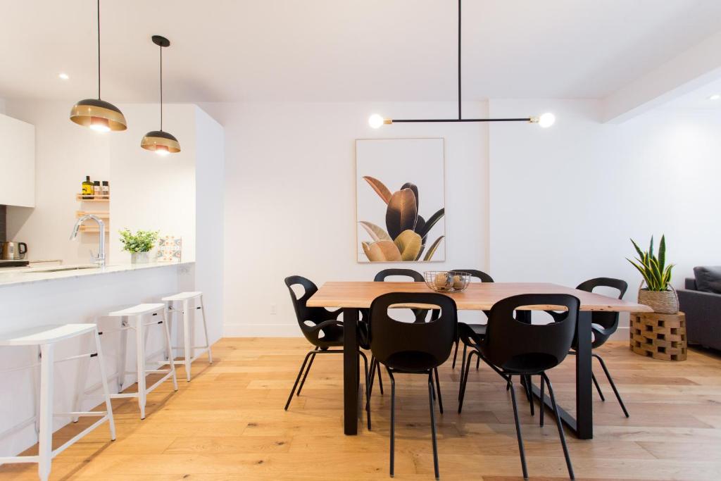 蒙特利尔Hip, Stylish Apartment in Little Italy by Den Stays A的用餐室配有木桌和黑椅子