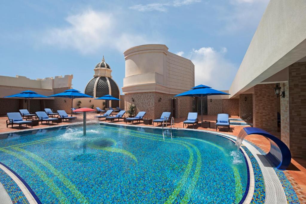 阿布扎比Royal Rose Abu Dhabi的屋顶游泳池,配有椅子和遮阳伞