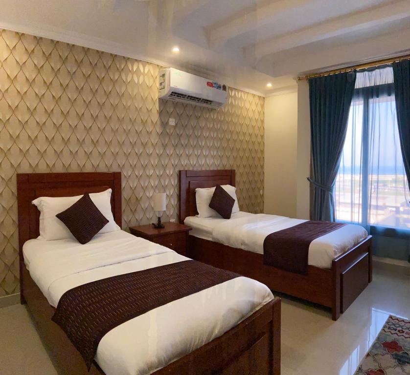 阿可贺巴درة المساكن للآجنحة الفندقية - الواجهة البحرية的酒店客房设有两张床和窗户。