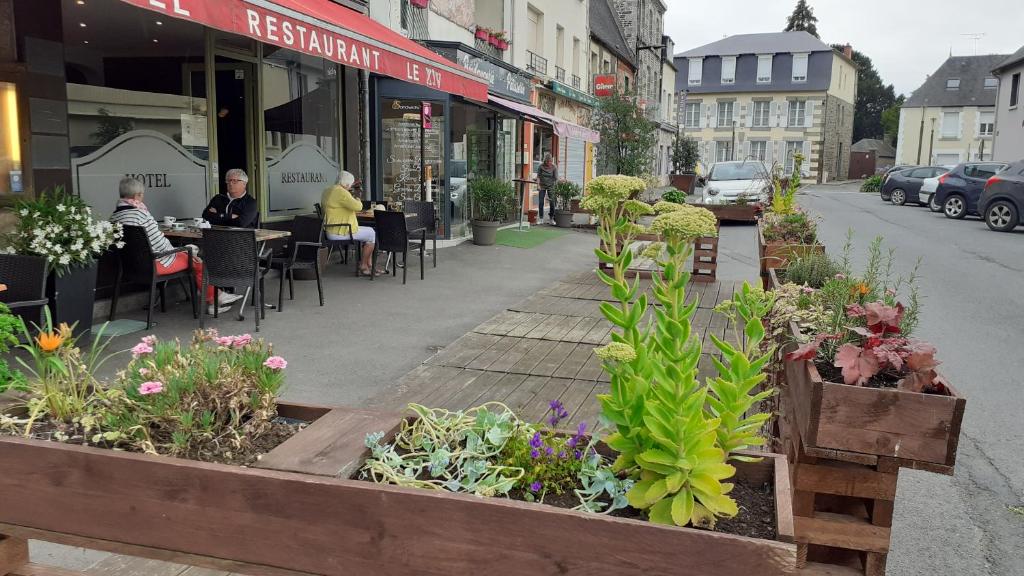 蓬托尔松Le XIV酒店的人行道上一条街道,街道上摆放着桌椅,种植着植物