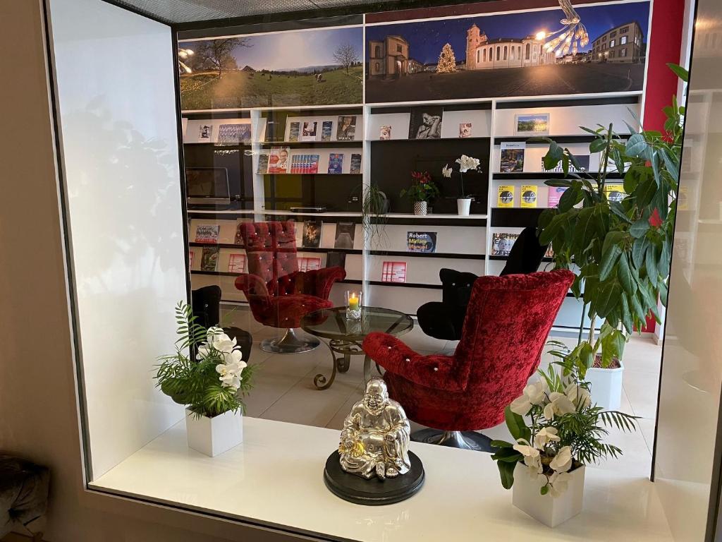 圣加仑Boutique City Hotel Gallo的商店里一面镜子,上面有红色椅子和植物