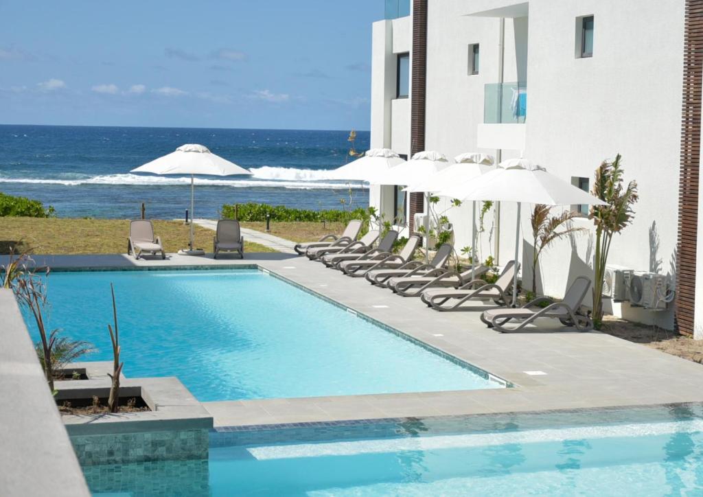 Poste LafayetteEastern Blue - Sea View Luxury Apartment的一个带椅子和遮阳伞的游泳池以及大海