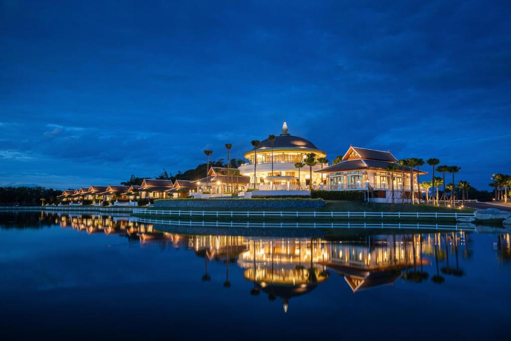 清迈Thantara Resort Chiang Mai的一座在夜间水面上灯亮的大建筑