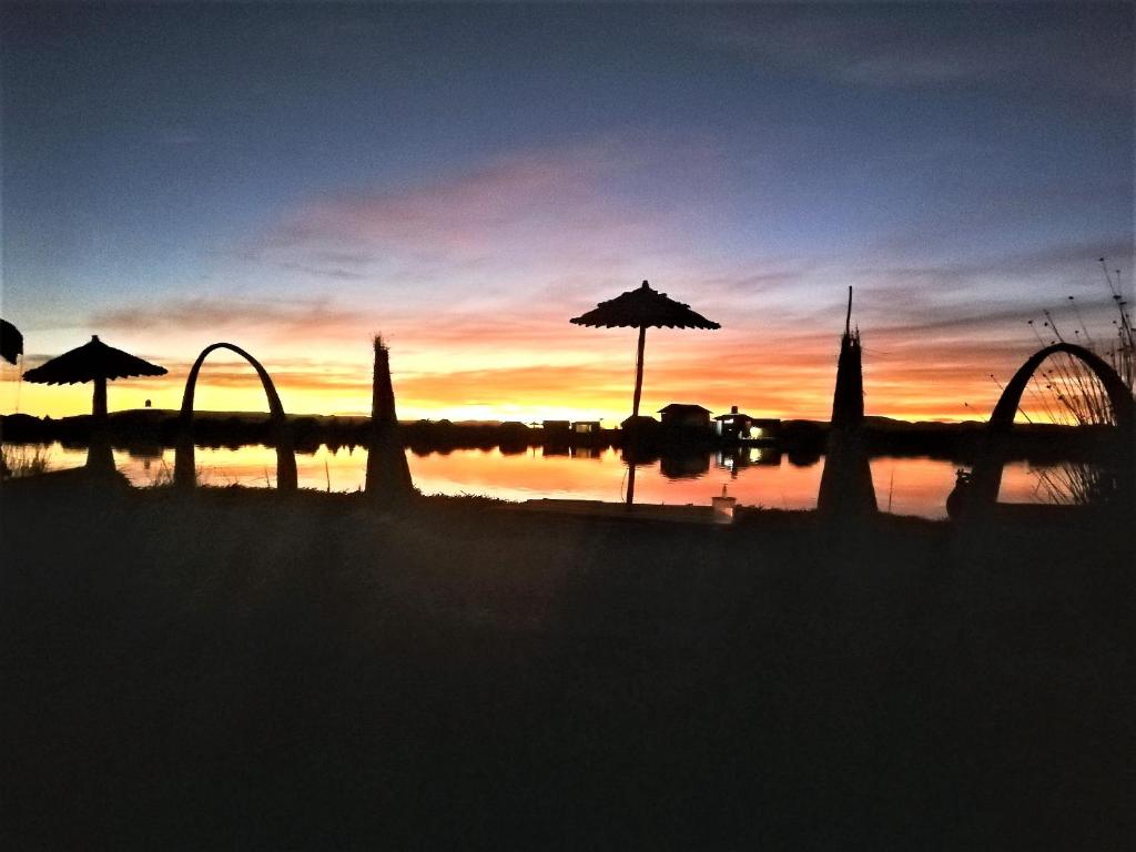 普诺Room in Lodge - Lucsay Titicaca Lodge的太阳落在水体上,有雨伞