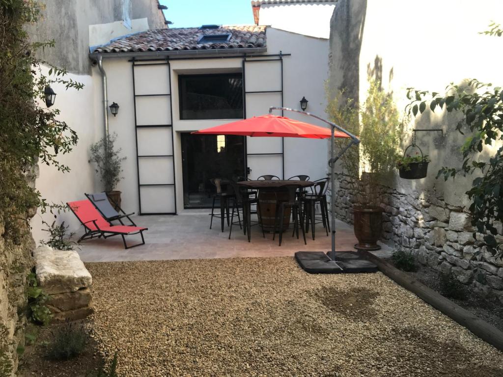 塞雷斯特La Bourgade的庭院配有带红色遮阳伞的桌子