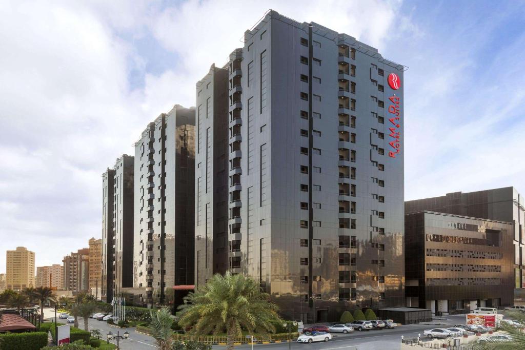 阿吉曼Ramada Hotel & Suites by Wyndham Ajman的上面有红色标志的高大的白色建筑