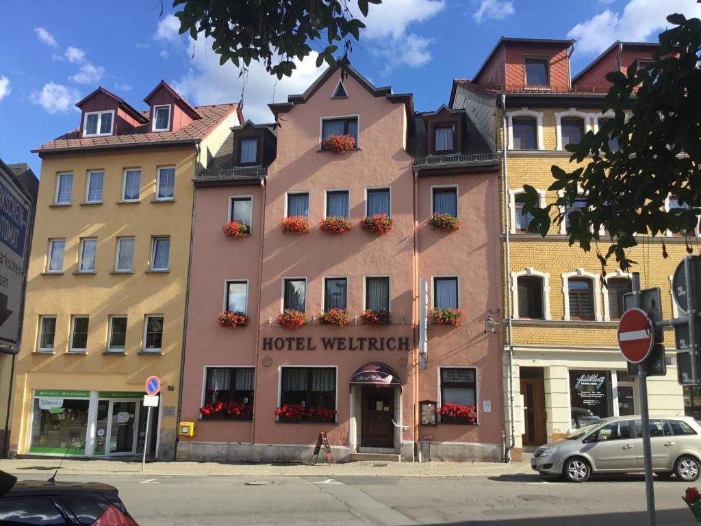 萨尔费尔德Hotel Weltrich的城市街道上的酒店大楼,有车辆停放