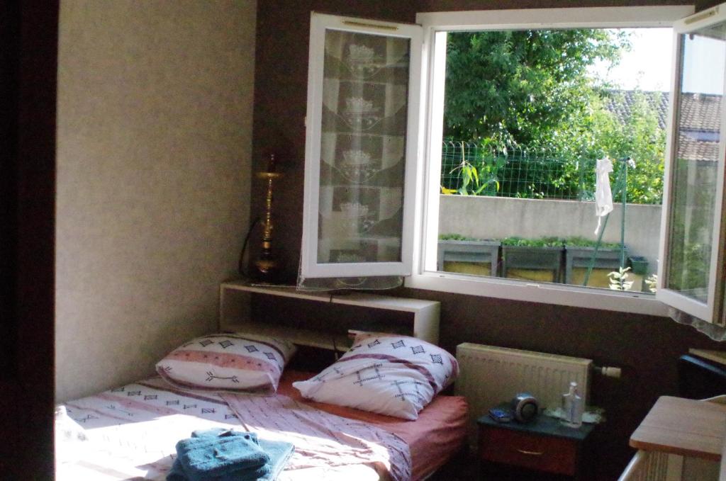 瓦朗斯Chambre chez l'habitant的卧室配有带枕头的床铺和窗户。