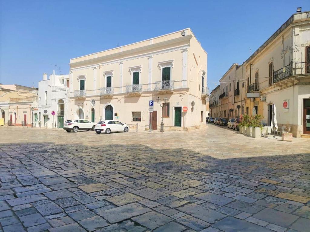 梅萨涅Antico Palazzo Murri的一条鹅卵石街道,汽车停在建筑前