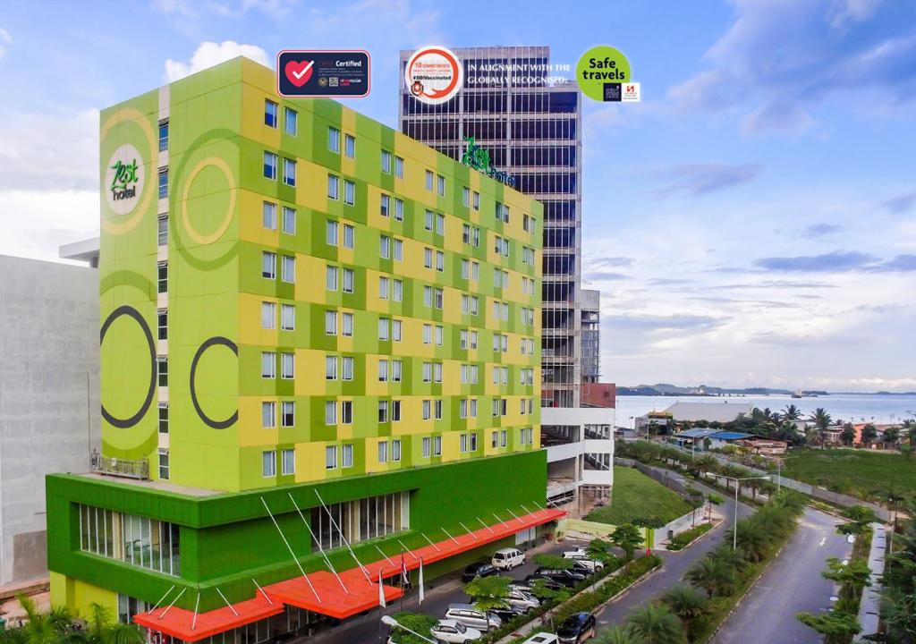 名古屋Zest Harbour Bay Batam by Swiss-Belhotel International的街道旁的一座黄色和绿色建筑