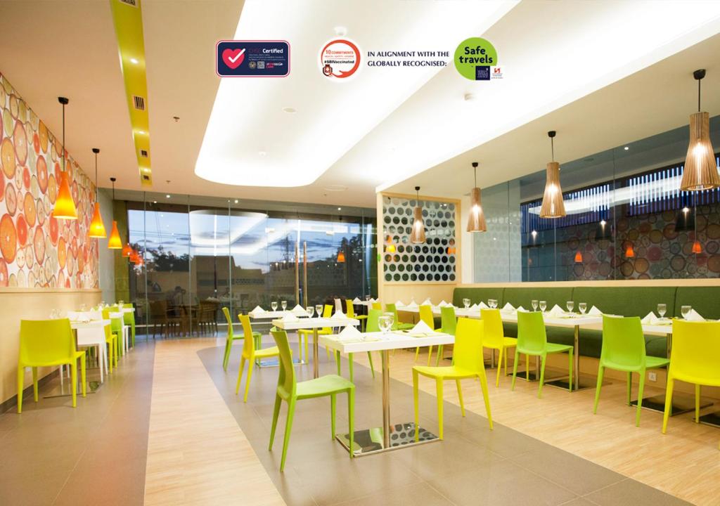 泗水Zest Jemursari by Swiss-Belhotel International的用餐室配有桌子和黄色椅子