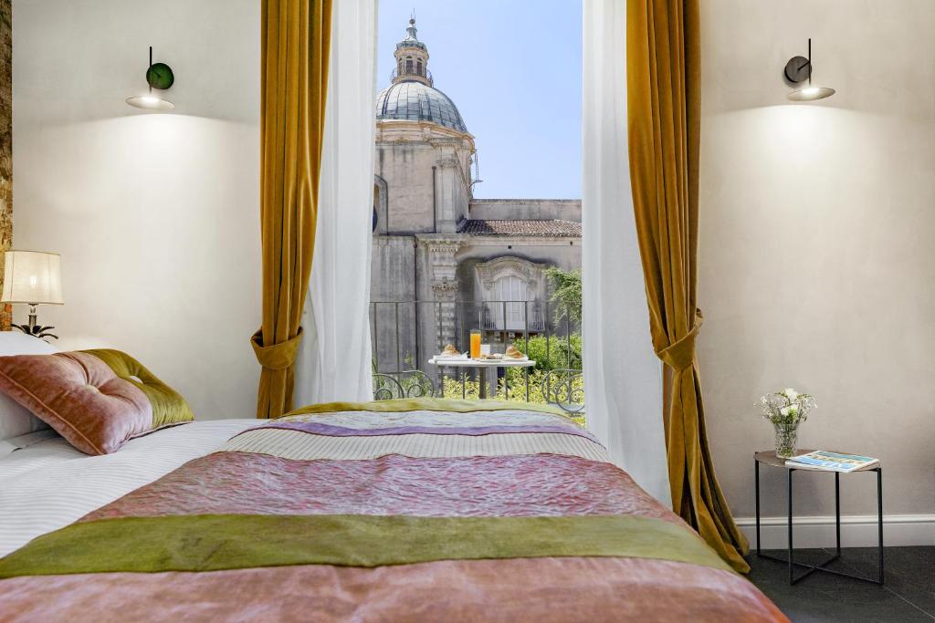 拉古萨Relais Antica Badia - San Maurizio 1619的一间卧室配有一张床,享有建筑的景色