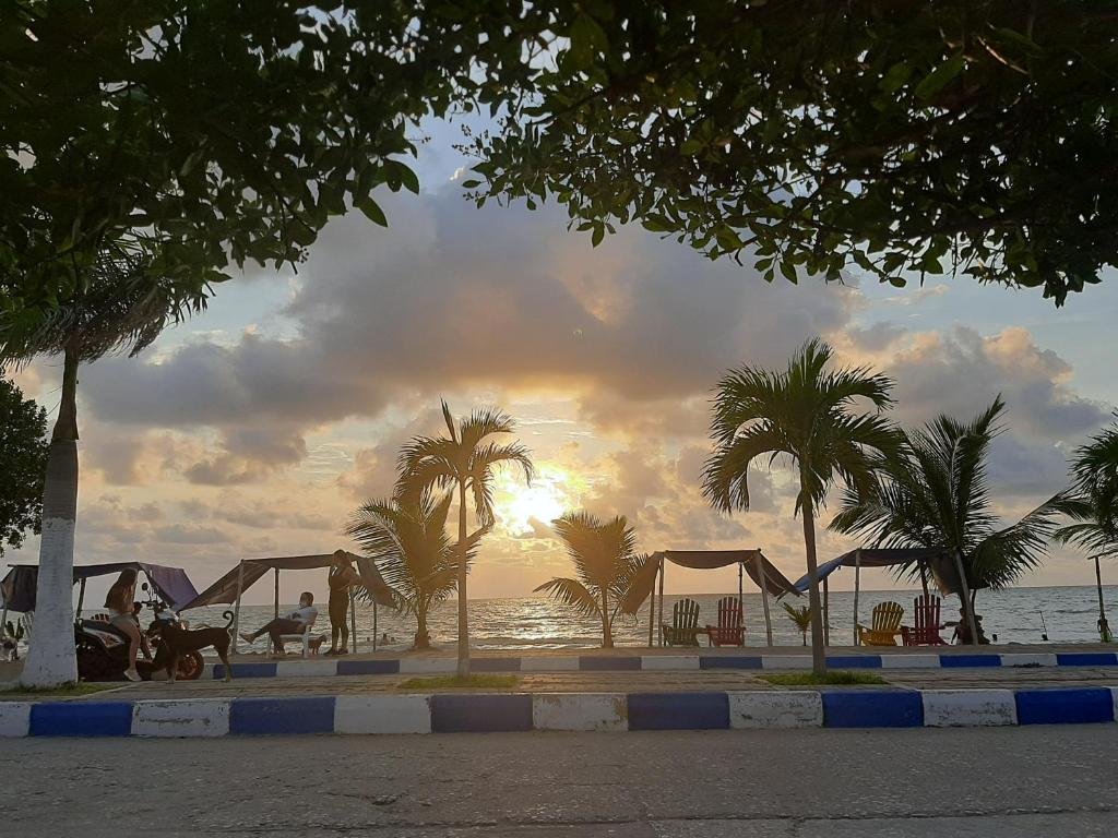 托卢Hotel Don Toño Tolú的棕榈树和帐篷海滩上的日落
