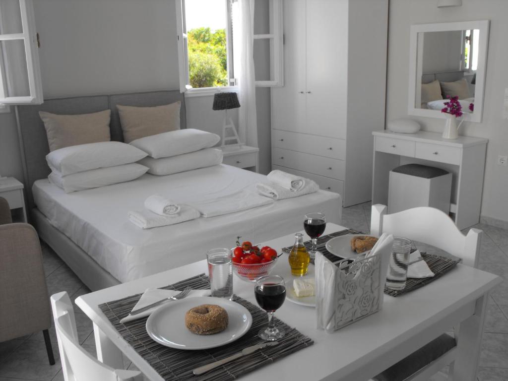 阿达玛斯米洛斯湾套房酒店的白色的客房设有一张床和一张带食物的桌子