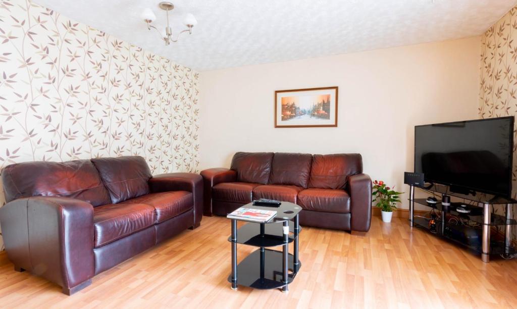 伯明翰Room near to Birmingham city centre with parking的客厅配有两张真皮沙发和一台平面电视
