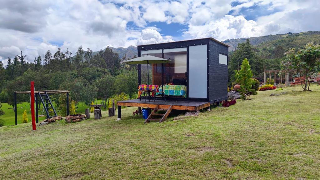 瓜塔维塔Iraca Glamping的坐在田野顶上的黑色小房子