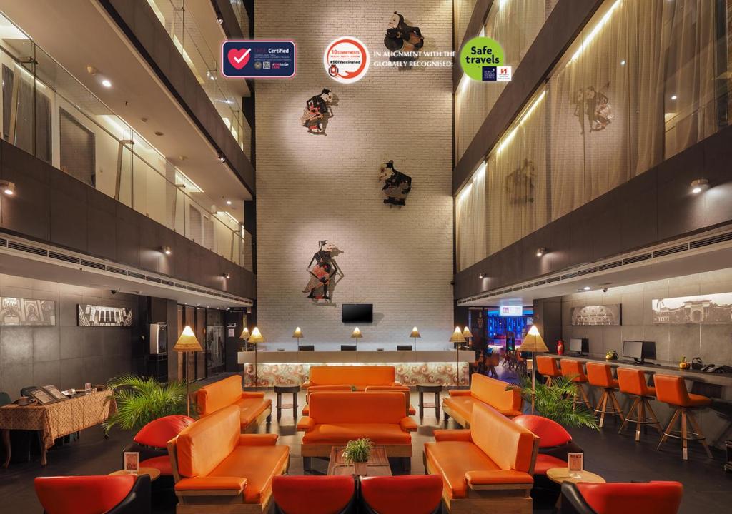 棉兰瑞士-贝林美丹酒店的酒店大堂设有橙色椅子和酒吧
