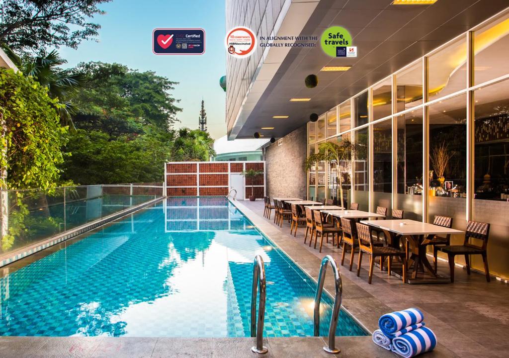 雅加达格玛腰兰瑞士贝林酒店的一座带桌椅的游泳池位于酒店大楼旁