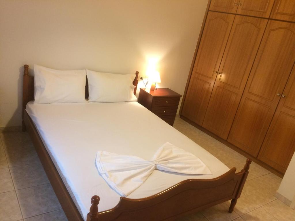 EllinikónGuesthouse "Athina"的一间卧室配有一张带白色床单的床和床头柜。