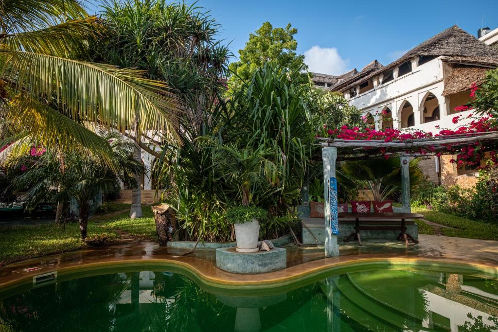 拉穆香蕉旅馆及健康中心的花园内的一个游泳池,花园内有长凳和一座建筑
